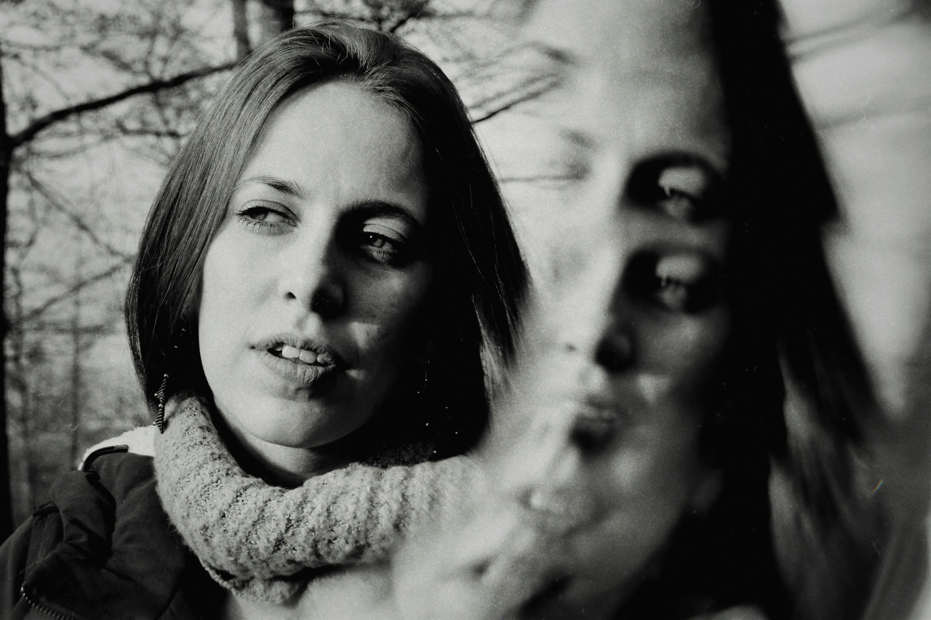 A reflective artistic black and white portrait of a woman outdoors, conveying introspection.