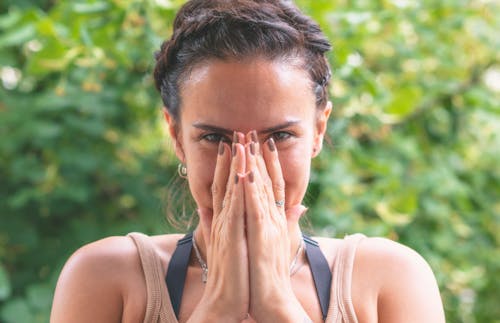 Free A Woman in Brown Tank Top Covering Her Face With Her Hands Stock Photo