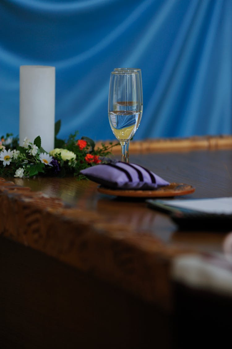 A Champagne In Glass Near Candle With Flowers