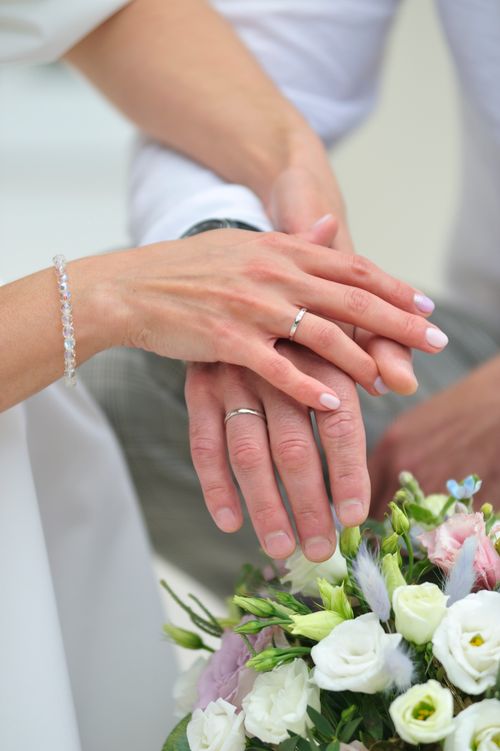 Free Close-up of newlyweds' hands with wedding rings over a beautiful bouquet in an intimate setting. Stock Photo