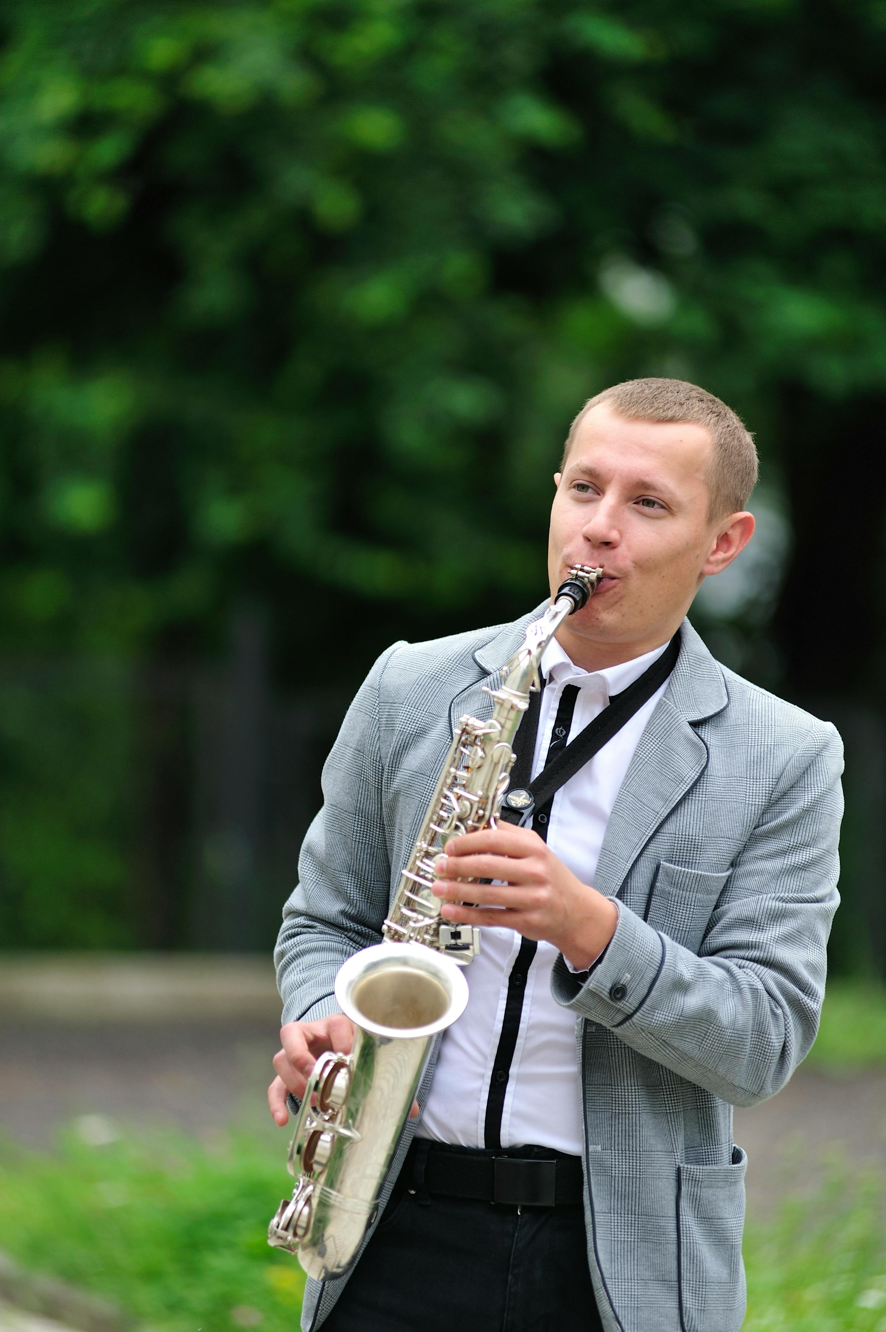 Musician playing saxophone in a suit outdoors, creating a lively atmosphere in Lviv.