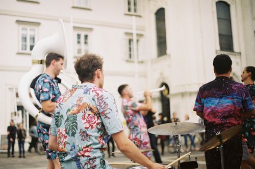 Free Energetic outdoor performance by a band wearing colorful shirts, playing various instruments. Stock Photo