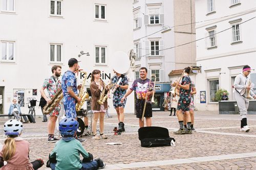 Free Vibrant street band in Hawaiian shirts playing instruments outdoors, entertaining a diverse crowd. Stock Photo