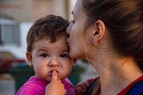 Free Heartwarming close-up of a mother kissing her child outdoors. Stock Photo