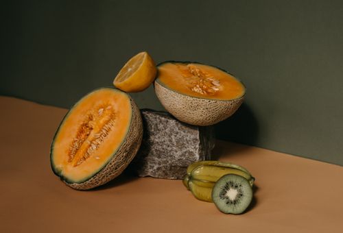 Free Elegantly arranged tropical fruits with a minimalist backdrop, showcasing the textures and colors of melon, kiwi, and carambola. Stock Photo