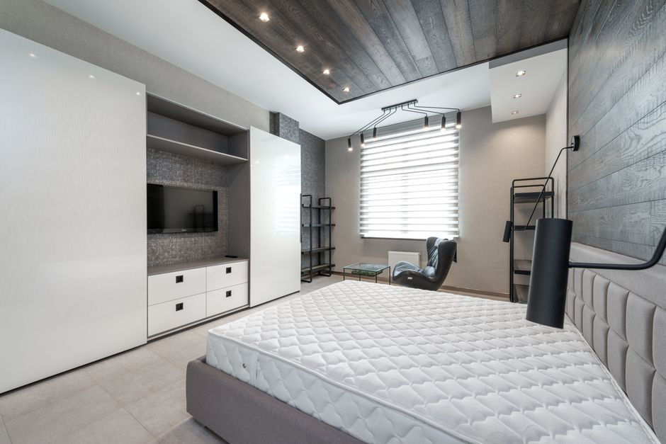 Schlafzimmer mit schlichtem Deckenspeicher über dem Kleiderschrank, helle Boxen und ruhige Optik
