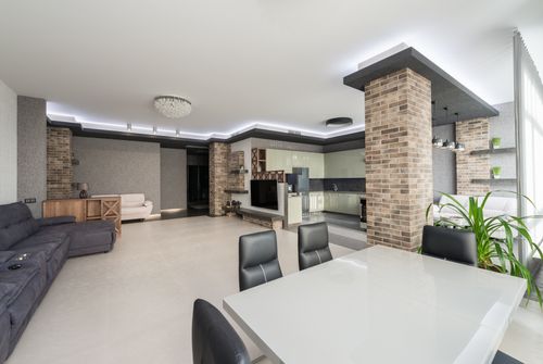 Free White table with chairs placed in spacious living room with comfortable couch and TV in modern apartment with kitchen and brick column Stock Photo