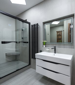 Elegant contemporary bathroom showcasing a glass shower, sleek sink, and large mirror for a spacious feel.