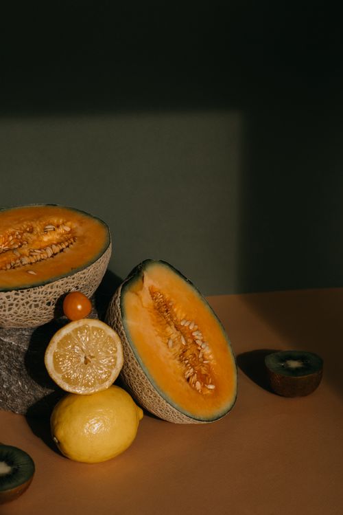 Free A variety of fresh fruits including sliced melon, lemon, and kiwi on a rustic table setting. Stock Photo