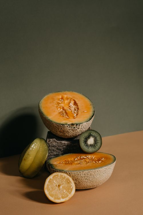 Free Vertical close-up of assorted fresh fruits, including cantaloupe, kiwi, and lemon. Stock Photo