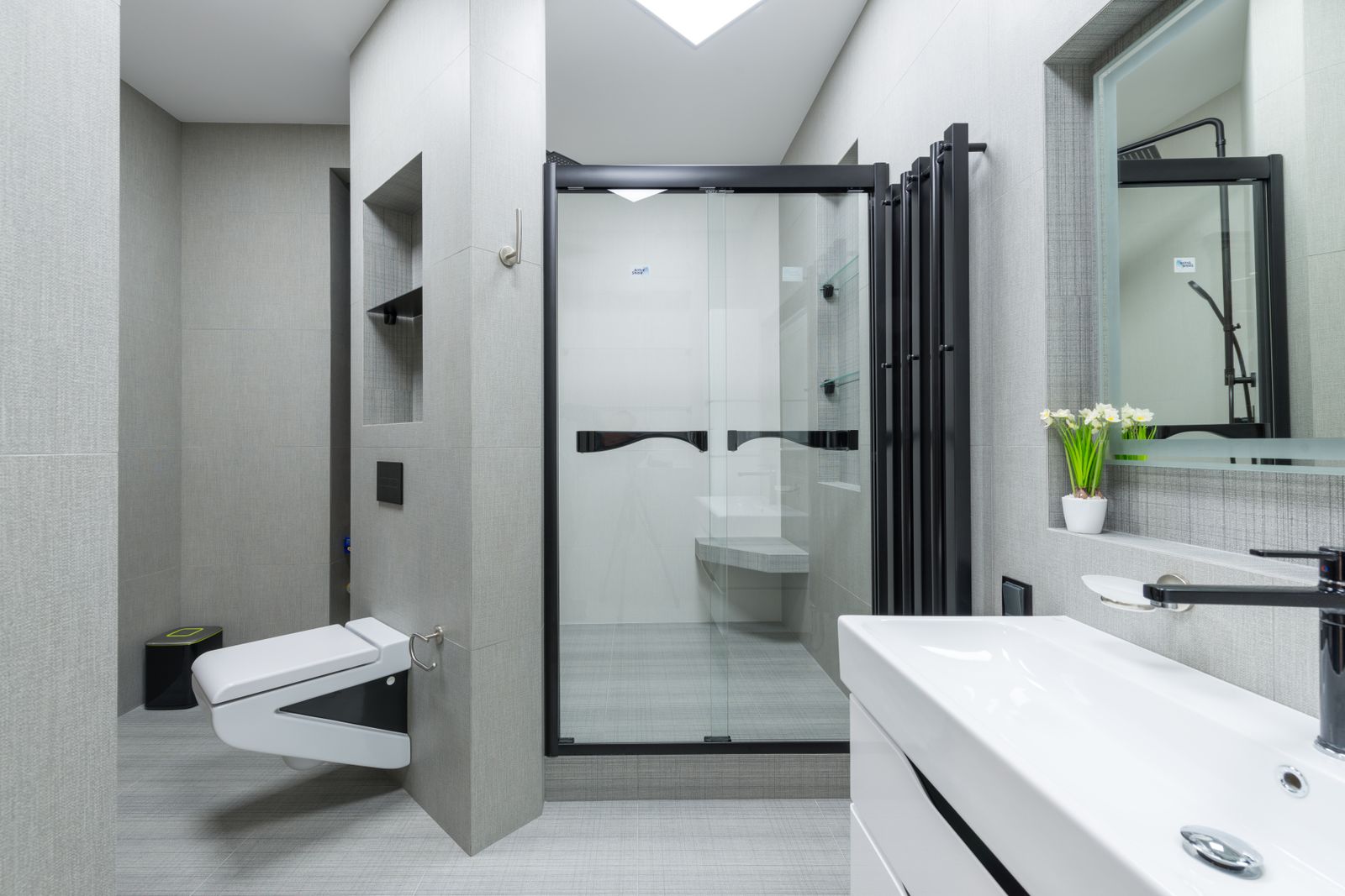 Spacious bathroom with wall-mounted sink, toilet and glass shower cabin