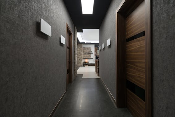 Long corridor with gray walls and wooden doors leading to light living room with decorations at home with stylish design