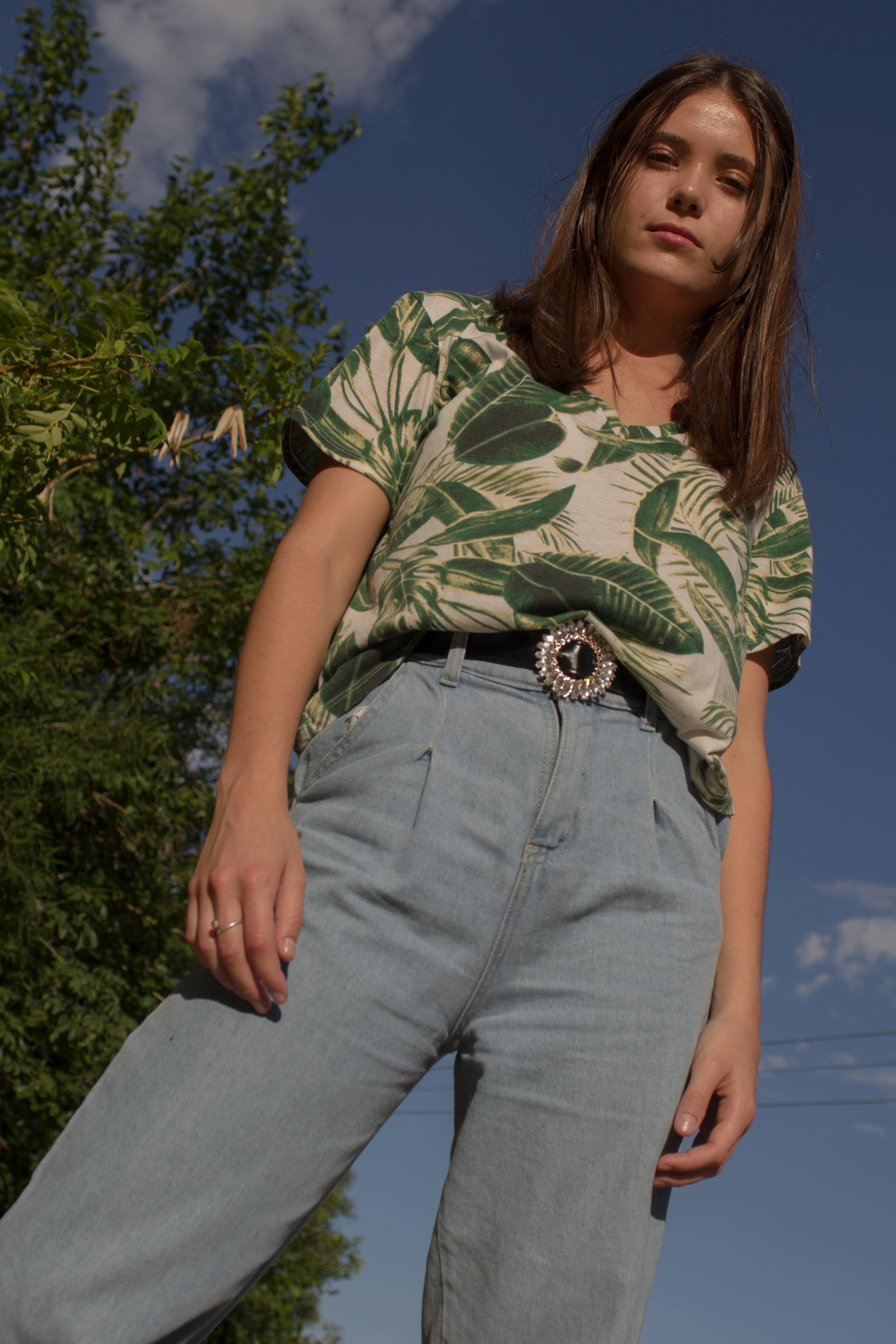 Woman in Green and White Floral Shirt and Blue Denim Jeans Standing