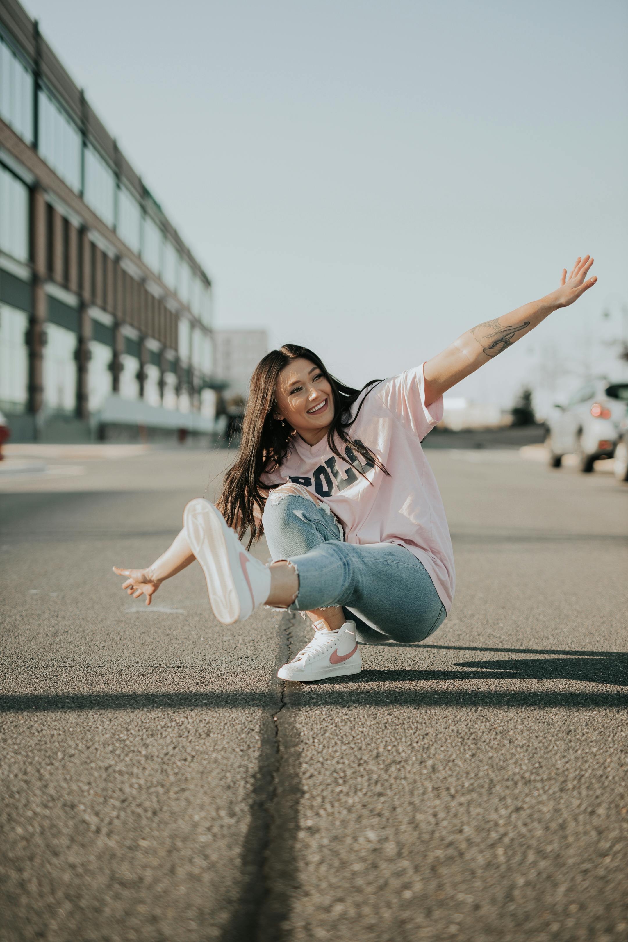 Happy woman in casual wear posing playfully on urban street. Bright and lively moment captured.