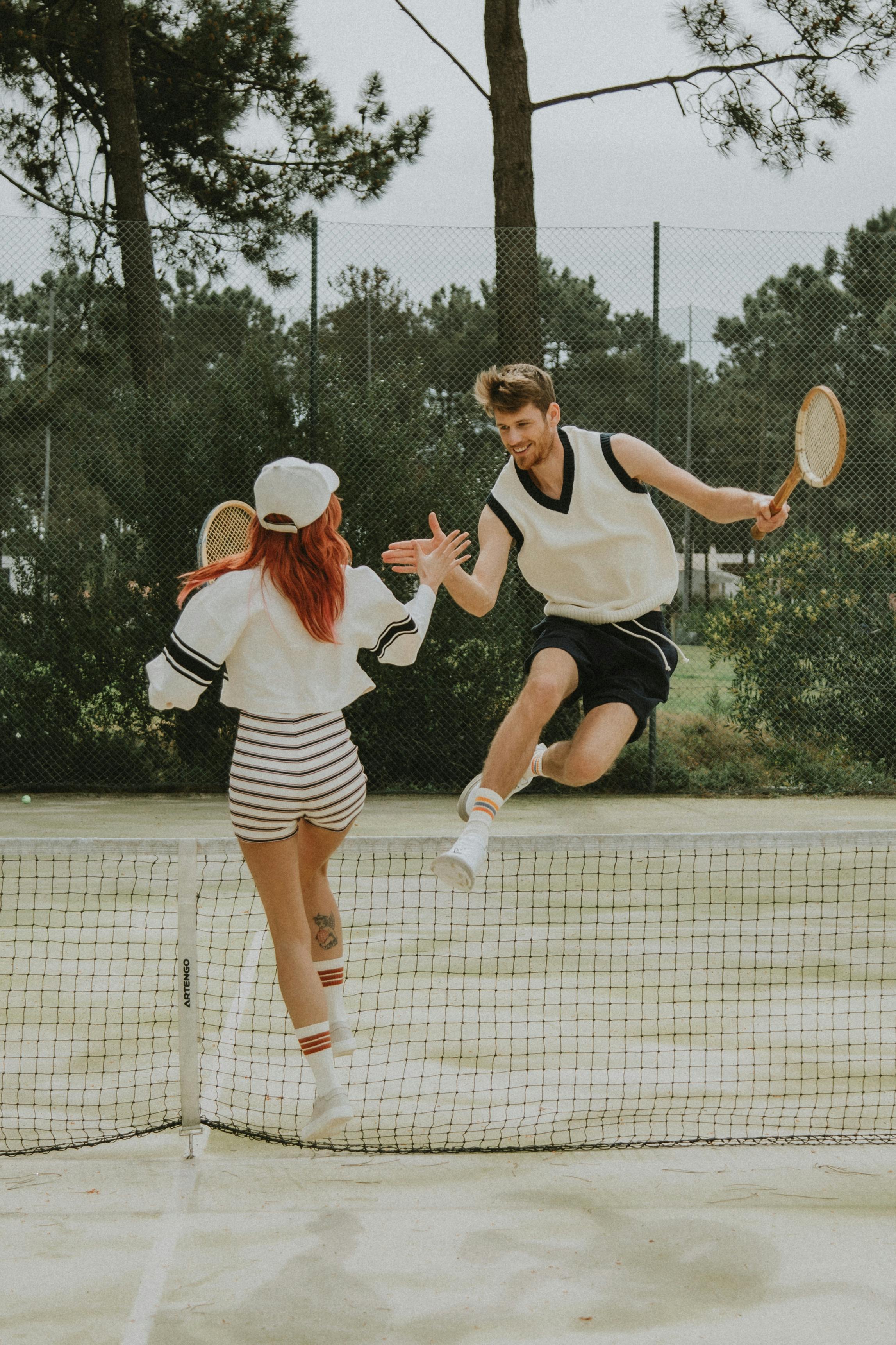 tennis players giving a high five while jumping
