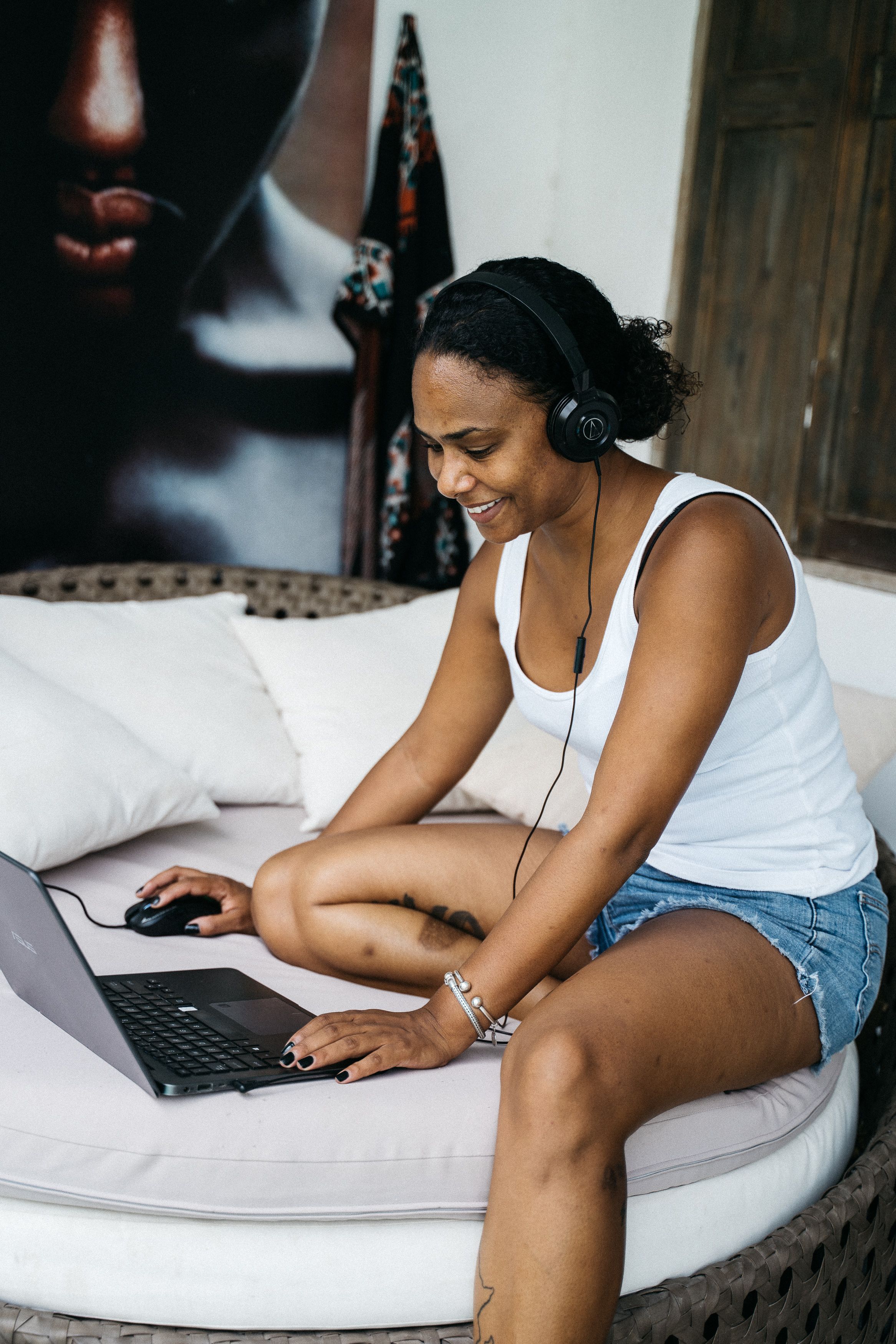 A Woman Using a Laptop while Wearing Headphones · Free Stock Photo