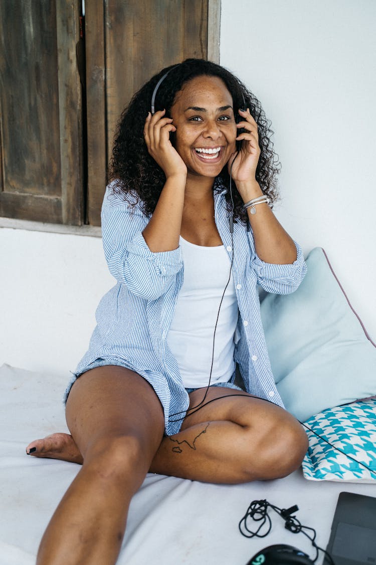 Woman Wearing Headphones Sitting On Bed