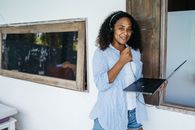 Woman in White Long Sleeve Shirt and Blue and White Striped Pants Holding Black Laptop Computer