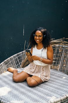 A joyful woman listening to music with headphones while relaxing outdoors on a sunny day.