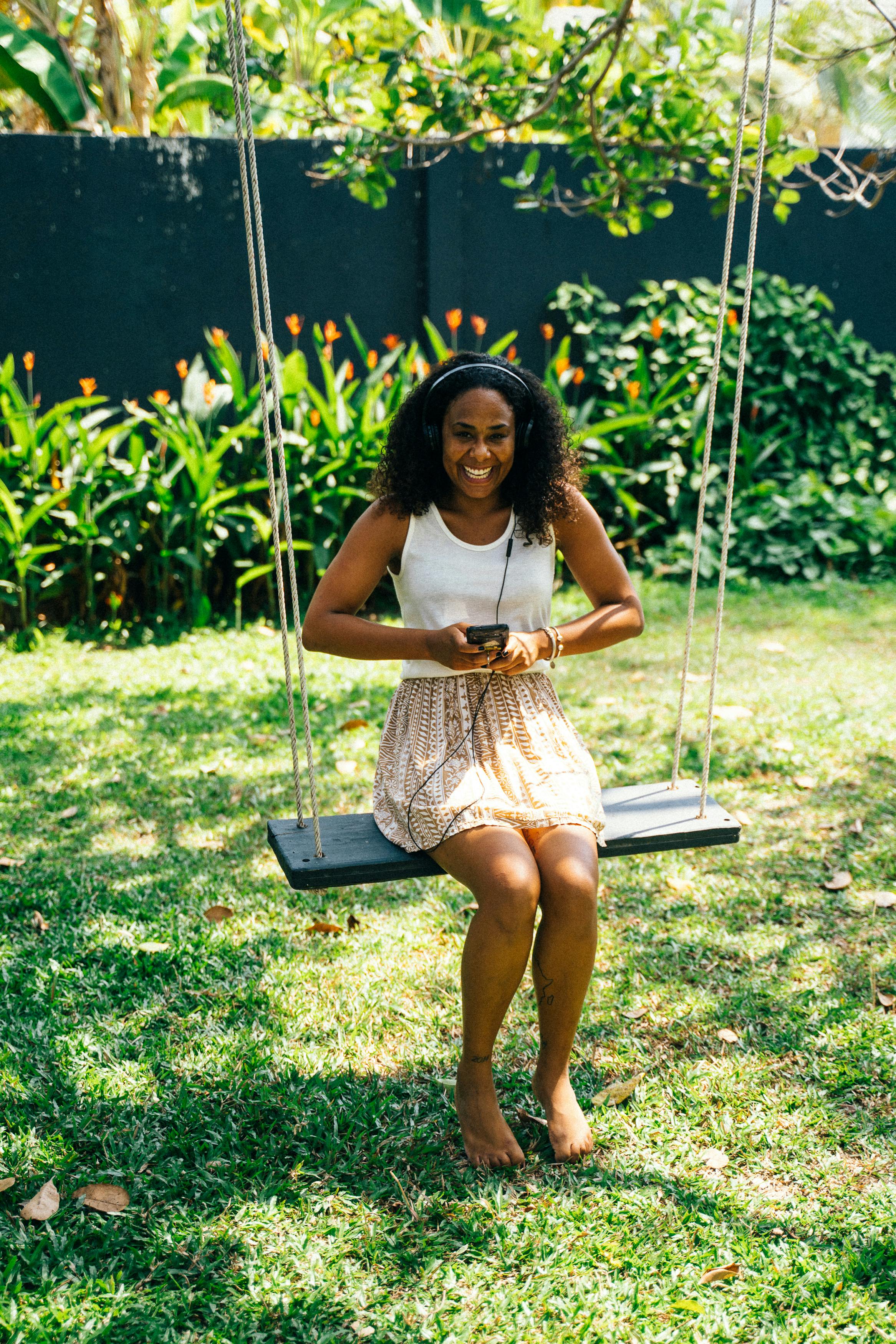 woman holding cellphone while sitting on a swing