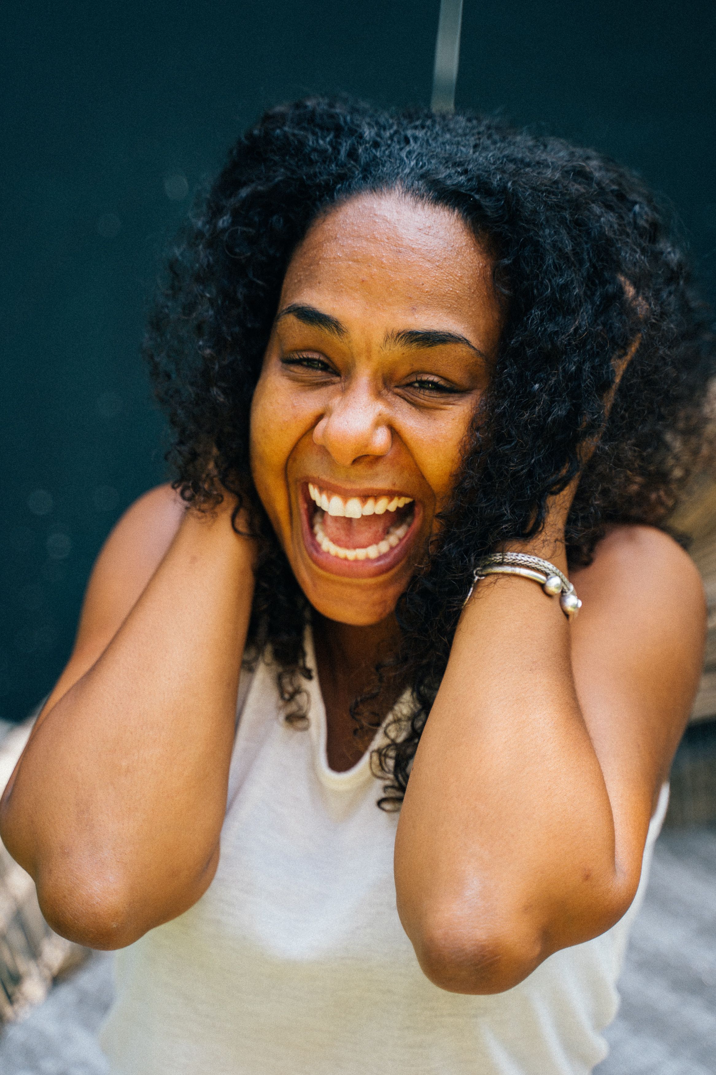 Portrait of a joyful African American woman laughing with hands on face.