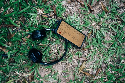Free Close-up of black headphones and smartphone placed on green grass outdoors. Stock Photo