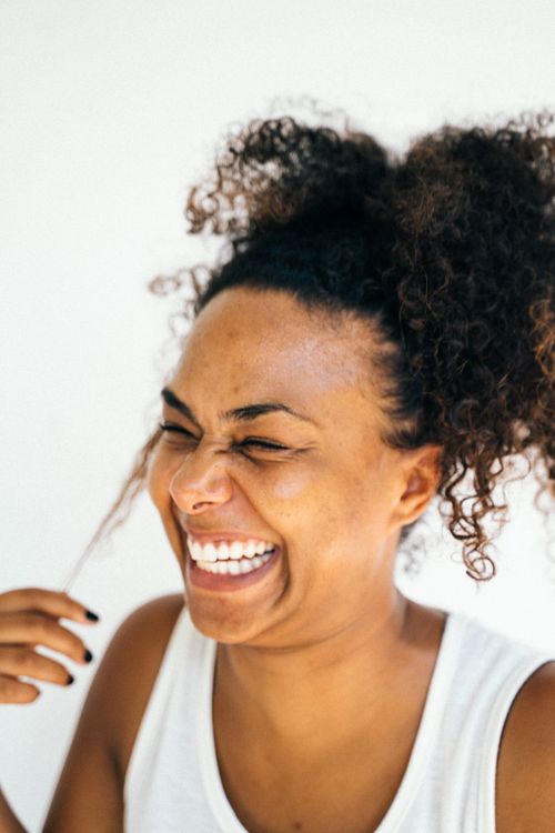Free Close-up of a happy woman with curly hair and a white tank top, radiating joy. Stock Photo