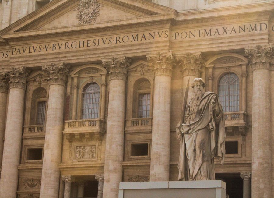 The majestic facade of St. Peter's Basilica in Vatican City featuring a prominent statue.