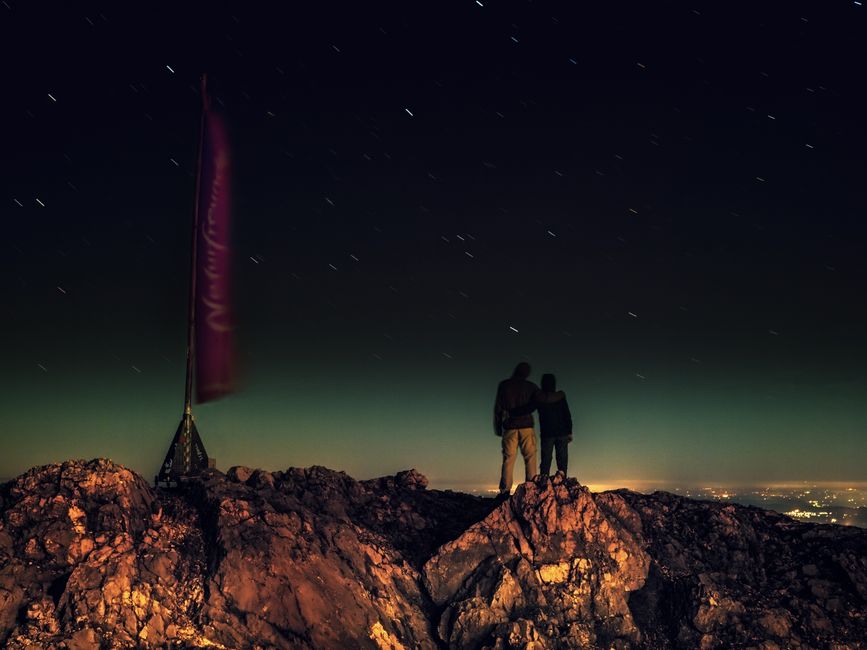 A couple gazing at the stars atop a mountain in Austria, creating a romantic and adventurous moment.