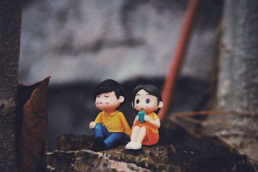 Cute couple figurines with boy and girl placed on rough surface near aged building with metal details on street of town