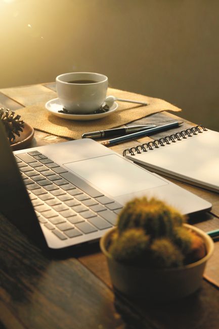 A warm sunlight-lit workspace with a laptop, coffee cup, and notebook. Perfect for productivity and ambiance.