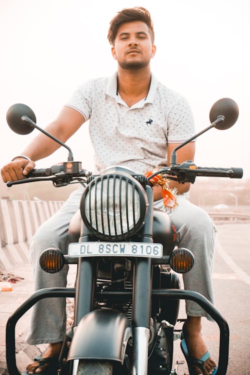Photo of a Man in a White Shirt Riding a Motorcycle