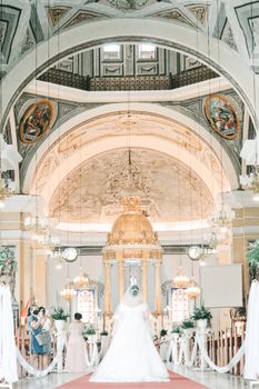 Stunning bride walking down the aisle in a beautifully decorated historic cathedral.