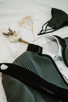 Close-up of elegant wedding attire with a face mask and floral boutonniere, symbolizing a pandemic wedding.