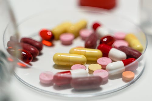 Red and Yellow Medication Pill on White Ceramic Plate