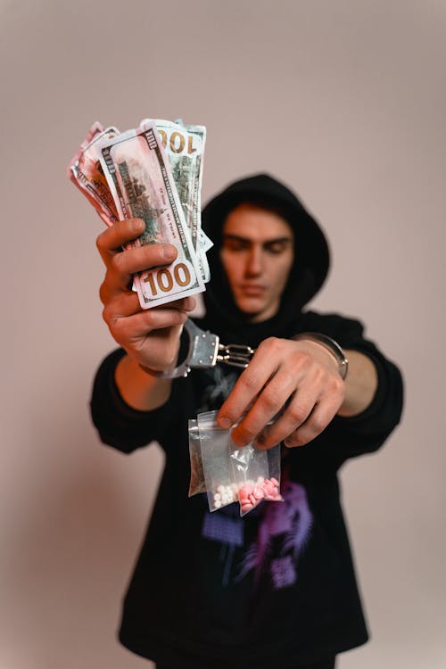 Free A Man in Handcuffs Holding Cash and Illegal Drugs Stock Photo