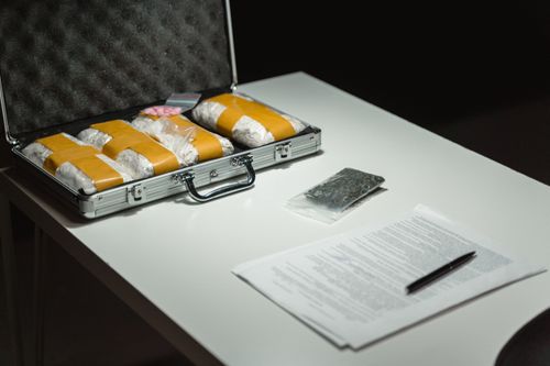 Free Briefcase with packages and documents on a table, suggesting illegal activity or crime scene investigation. Stock Photo