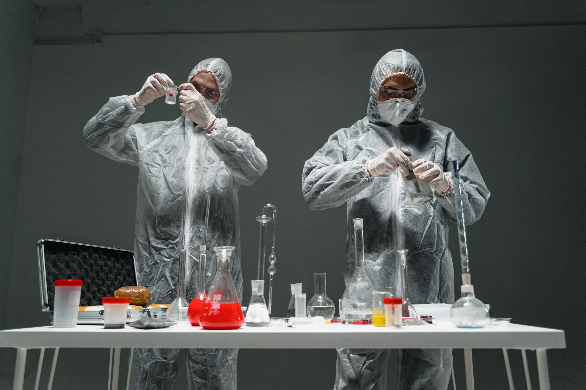 Persons Wearing Personal Protective Equipment Testing a Specimen