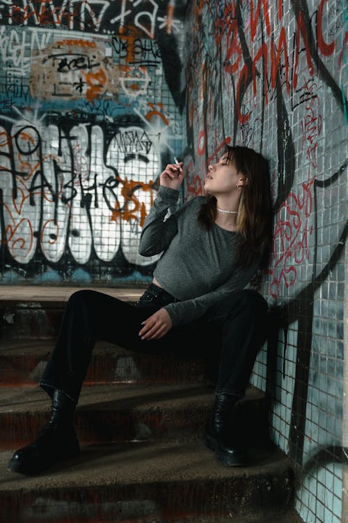 Woman in Gray Long Sleeve Shirt and Black Pants Sitting on Brown Wooden Bench