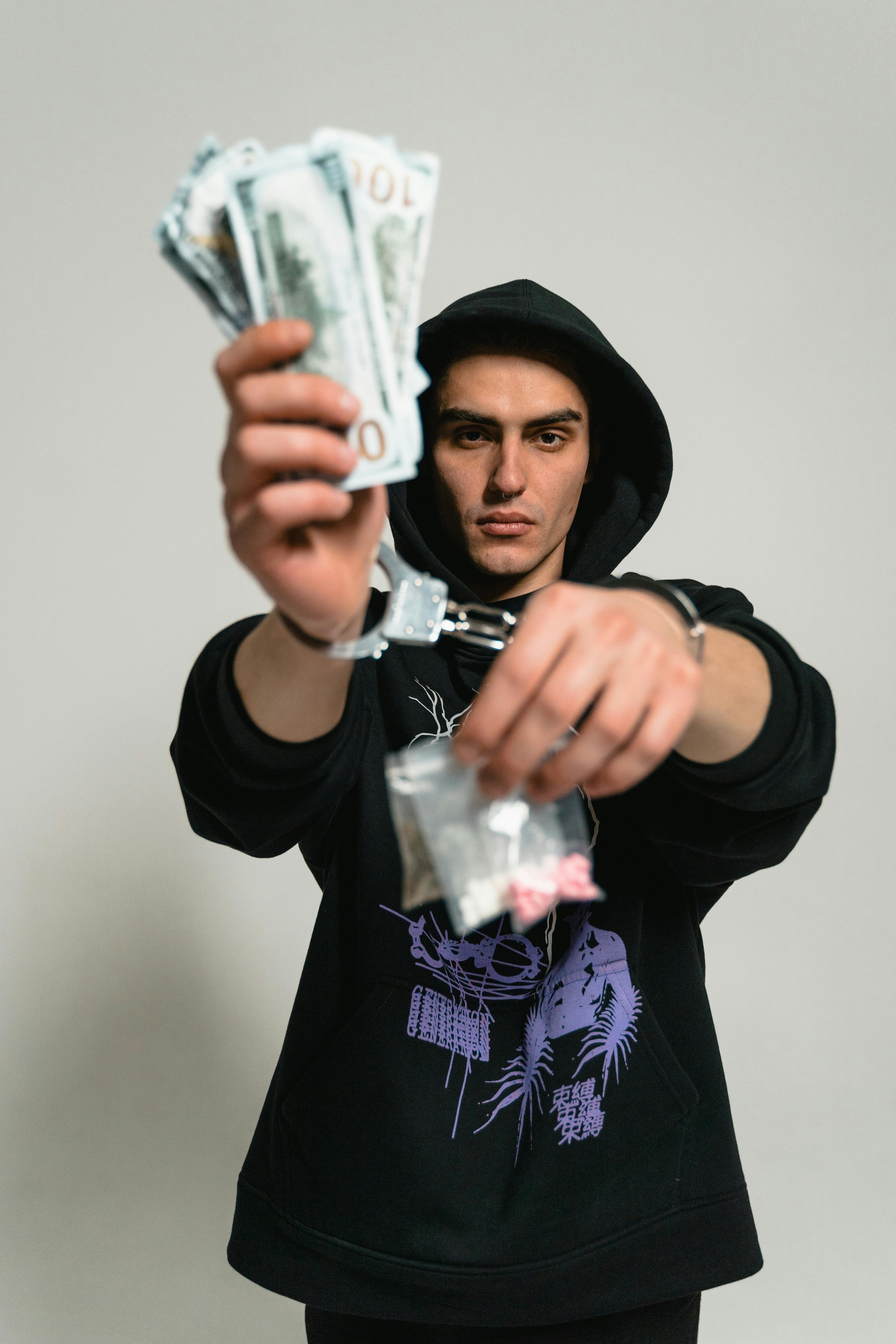 A Man in Black Hoodie Sweater Wearing Handcuffs while Holding Money and  Drugs · Free Stock Photo