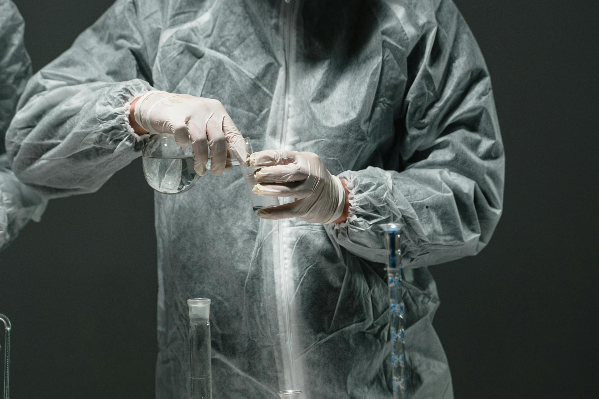 A scientist in PPE performs a precise chemical experiment in a controlled laboratory environment.