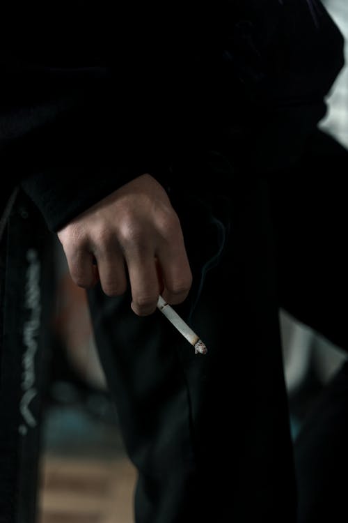 Person in Black Long Sleeve Shirt Holding Cigarette Stick