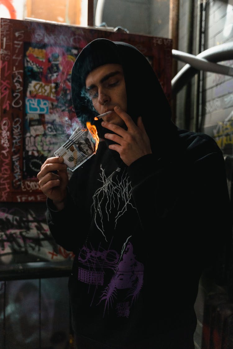 A Man Holding Burning Money While Smoking 