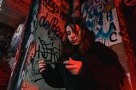 Woman in Black Long Sleeve Shirt Leaning on Wall With Graffiti