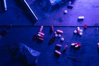 Red and White Medication Pill on Black Wooden Table