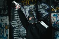 Man in Black Hoodie Holding White and Black Gun