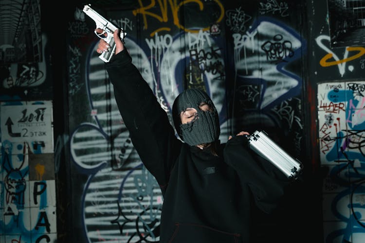 A Woman With Mask Holding A Briefcase And Gun