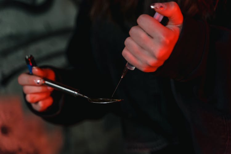 A Person Using Spoon And Syringe In Consuming Illegal Substance