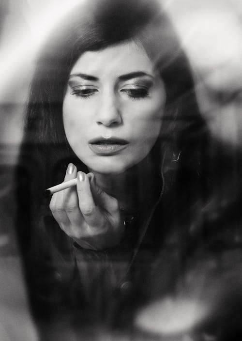 Pensive woman with makeup smoking cigarette