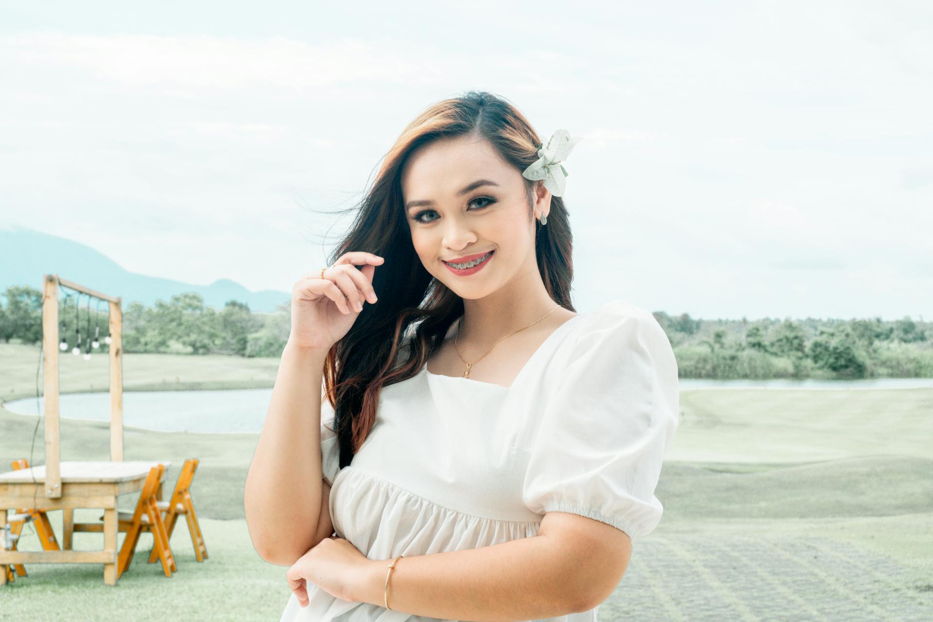 Asian woman with braces smiling and posing outdoors on a sunny day.